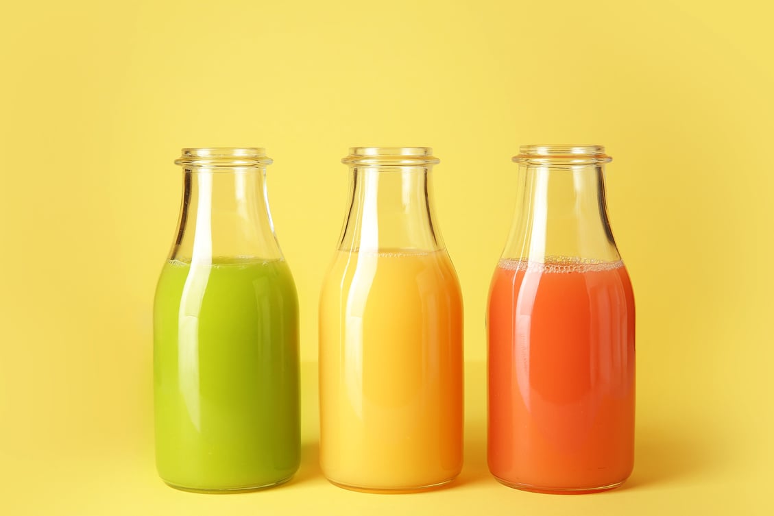 Bottles of Fresh Juice on Yellow Background